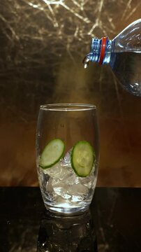 Sparkling water pouring to ice and cucumber 50fps slowed