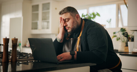 Man, chef and laptop with stress in kitchen for bad mistake, fatigue or burnout at home. Male...