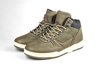 Khaki or olive green high-top sneakers against a white background, featuring lace-up closures and durable construction for possible rugged wear or outdoor activities