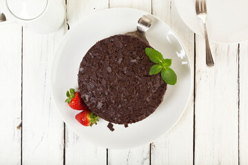 Whole Chocolate Cake and strawberries on wooden table, top view