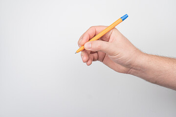 Hand holding a yellow pencil with an eraser, writing or drawing on a light grey boardpaper...