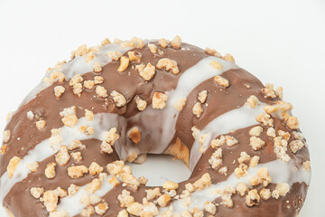 Centrally positioned chocolate doughnut with horizontal white icing and nut sprinkles against a neutral backdrop.