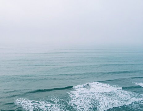 Blurred Sea Foggy Morning Coast with Aerial Wave Patterns and Soft Glow for Dreamy Shore Background