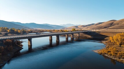 Obraz premium A scenic expressway bridge spanning over a river, with clear skies above and vehicles moving across, symbolizing connectivity and long-distance travel