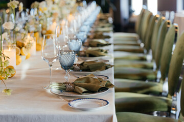 Tables with green napkins, glasses, flowers, and chairs. Special clips on the napkins. Restaurant atmosphere.