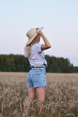 Woman sitting calmly in a golden wheat field during sunset, reflecting on life and nature's beauty...
