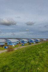 Row of modern blue bungalows facing the river under cloudy sky
