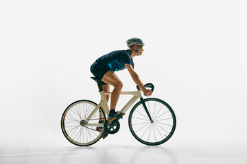 Side view image of young concentrated man, professional cyclist in motion on bicycle, riding...