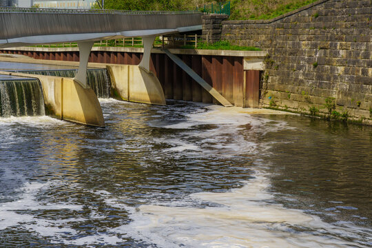 Industrial foamy water discharge into River Aire at a weir near Leeds, West Yorkshire, UK.