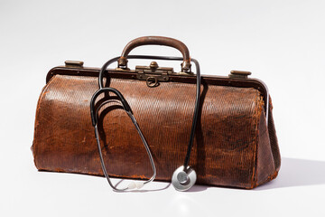 Vintage doctor bag and stethoscope resting on white background