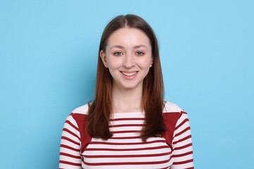 Portrait of happy teenage girl on light blue background