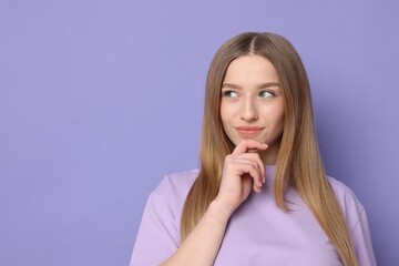 Fototapeta premium Portrait of thoughtful teenage girl on violet background. Space for text
