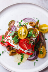 Greek salad stack with feta cheese, tomatoes, red onions and olives.