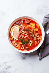 Traditional soup solyanka with smoked sausages, olives and potatoes.