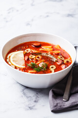 Traditional soup solyanka with smoked sausages, olives and potatoes.