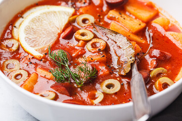 Traditional soup solyanka with smoked sausages, olives and potatoes.