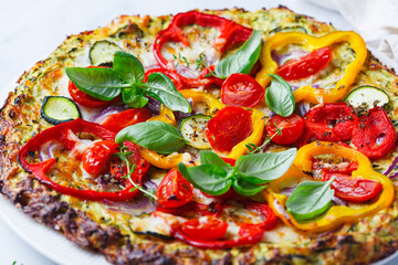 Vegan pizza on zucchini crust with vegetables and mozzarella.