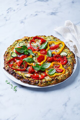 Vegan pizza on zucchini crust with vegetables and mozzarella.