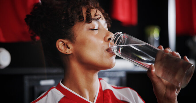 Girl, soccer player and drinking water with bottle in locker room for hydration, break or half time. Female person, athlete or thirst with refreshing mineral liquid for natural sustainability or rest