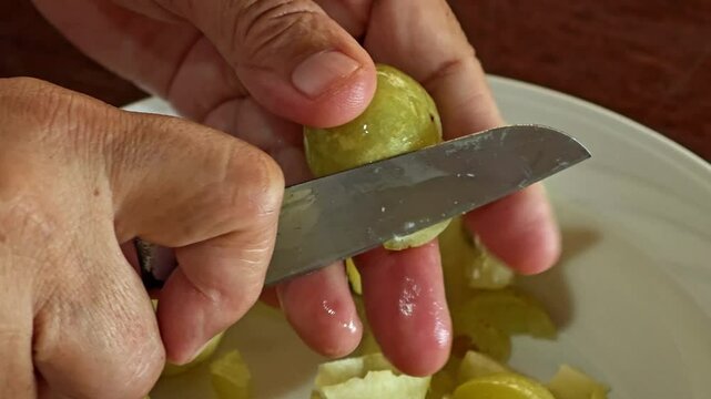 Cutting Indian gooseberry in a bowl.
