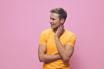 smiling man in yellow t-shirt looking aside standing on pink background digital detox concept...