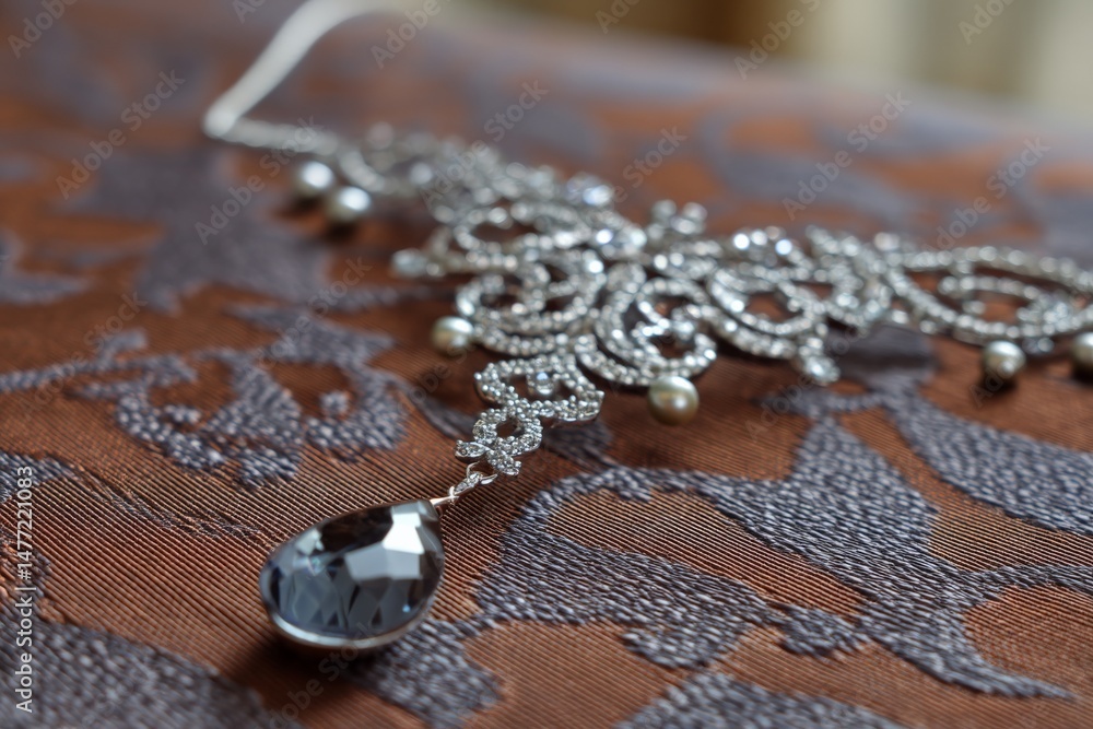 Poster elegant silver necklace with intricate design and a teardrop pendant displayed on textured fabric