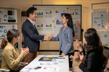 A man shakes hands with a woman in a suit