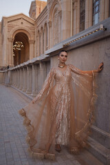 beautiful woman with dark hair in luxurious dress with accessories posing on the stairs of elegant...