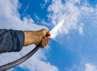 closeup man watering a garden with a hose
