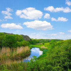river flow among green hills under blue cloudy sky
