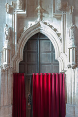 Entrance to the cathedral of white stone closed with red curtains