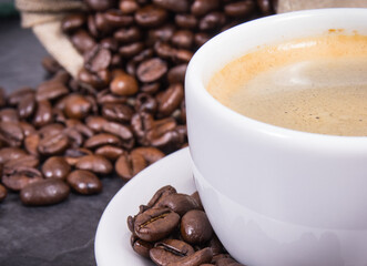 Coffee in white cup and roasted dark coffee beans in bag