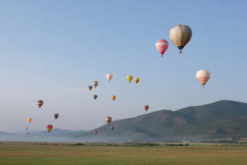 Fototapeta premium festival of hot air balloons in clear morning sky with sun shining on thousands of colorful balloons floating above