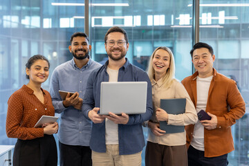 A diverse team of colleagues smiles with joy and confidence while looking at the camera in the office. Collaboration.