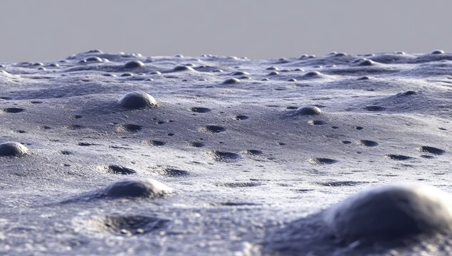 Lunar surface, dotted with bumpy,  rounded craters.  A  grayish-white landscape - Powered by Adobe