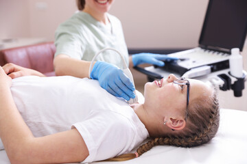 Obraz premium Sonographer conducting girl's thyroid gland ultrasound examination in clinic, closeup