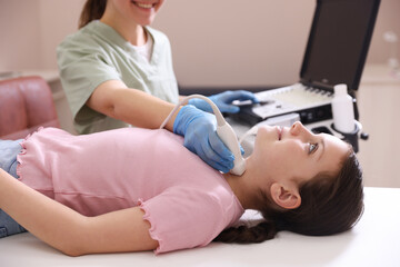 Sonographer conducting girl's thyroid gland ultrasound examination in clinic, closeup