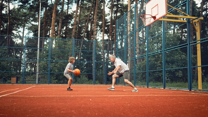 Sport, family and learning basketball with dad and son training on court outside for leisure...