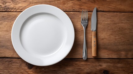 Top view of an empty white porcelain plate with cutlery on a wooden table with copy space image