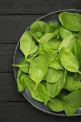 Fresh spinach leaves on black wooden background. Vertical photo