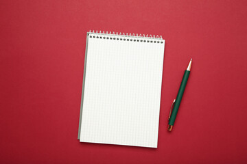 Notebook with pen on dark red background. Space for text