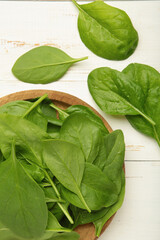 Spinach leaves in a wooden plate on white background.
