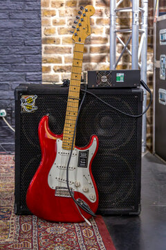 Red Fender Stratocaster guitar with a sticker-covered amp behind, featuring Dr. Martens branding &mdash; a bold mix of music and alternative style.