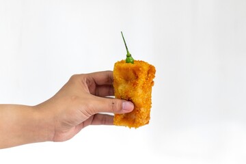 Hand holding a Risoles or Rissoles with green chili. A small croquette enclosed in pastry and...