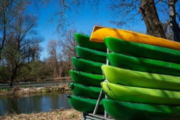 Colorful stack of green and yellow kayaks on a trailer, ready for adventure on the Nestos river in Paranesti, Greece. Outdoor water sport equipment prepared for a summer recreational activity.