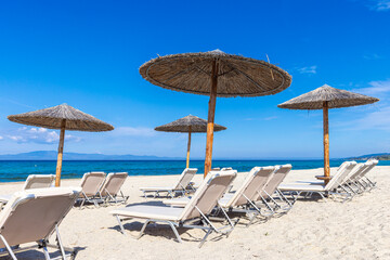 Sonnenliegen und Strohdächer am Strand von Kassandra