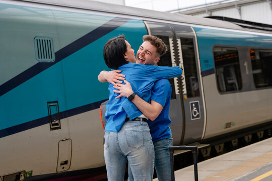 People reunite joyfully at the train station embracing after a long journey on a sunny day