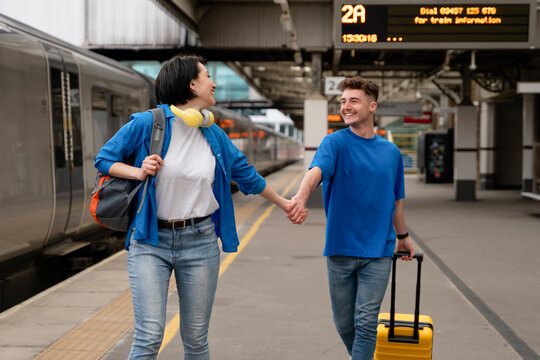 Couple enjoying time together at train station while preparing for travel in spacious terminal setting during morning hours
