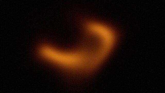 Black background with abstract orange neon light speckled grains, bright color gradient with soft texture