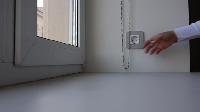 Close-up of womans hands lifting roller blinds on the window in a chain, opening curtains in good day